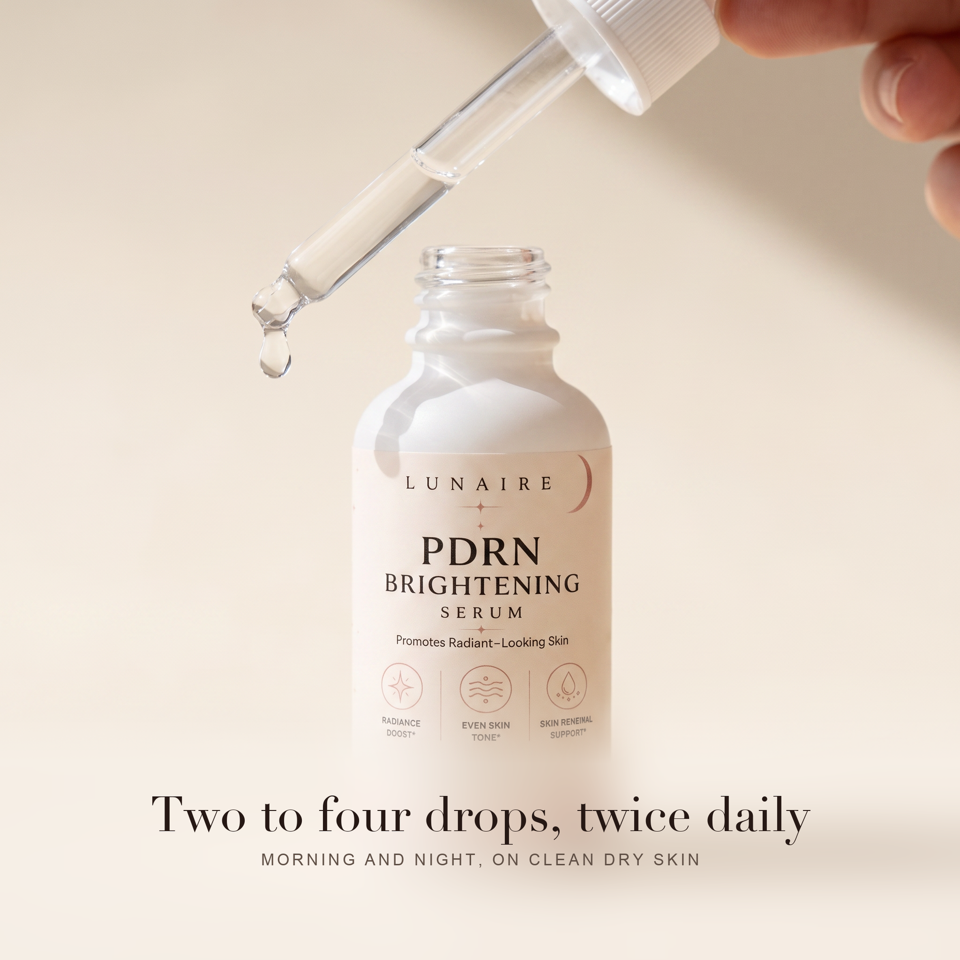 The glass dropper releasing a drop above the bottle. Two to four drops, twice daily, morning and night on clean dry skin.